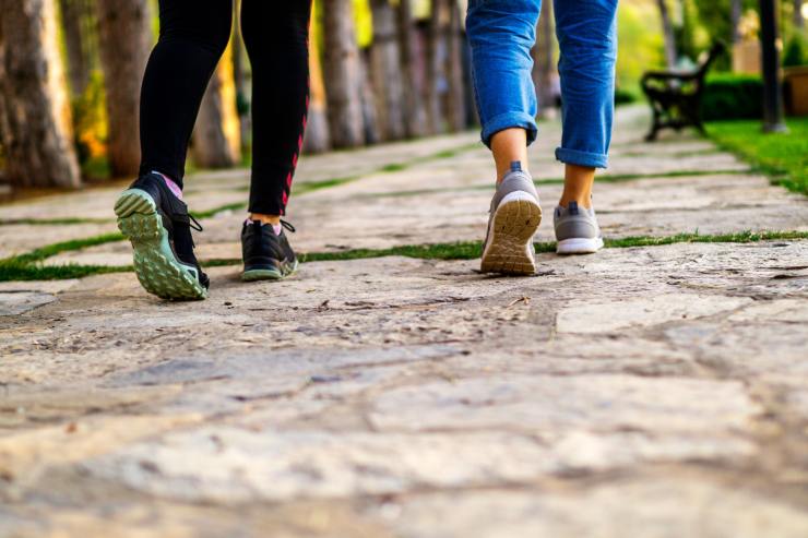 Gambe di due persone che camminano in un parco per sgonfiare la pancia
