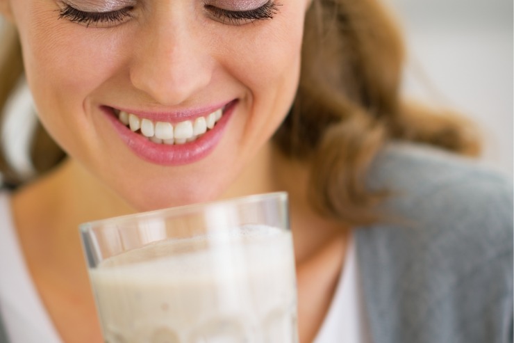 Donna sorridente che beve un frullato bianco