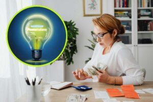 Una donna con gli occhiali che studia delle fatture e, in evidenza, il logo di Poste Energia