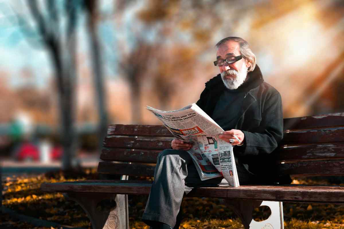 Pensionato che legge il giornale su una panchina