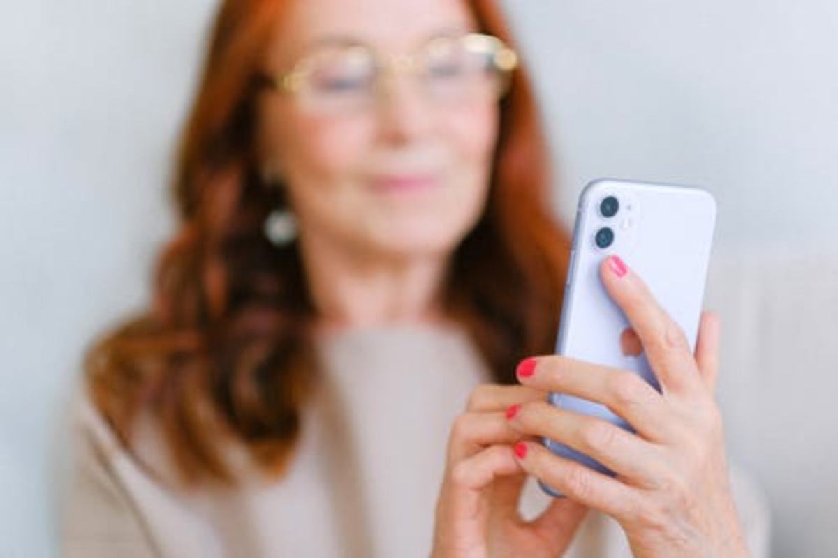 Una donna con gli occhiali e il telefono in mano