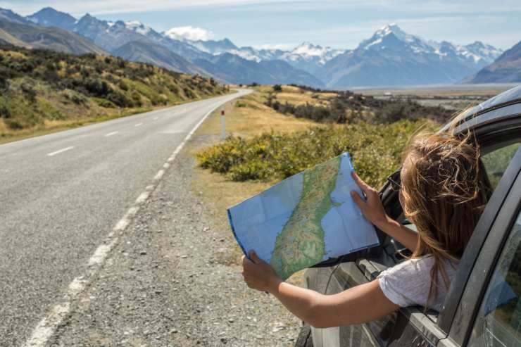 Ragazza che si affaccia dal finestrino dell'auto e guarda la mappa