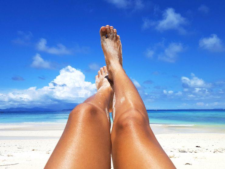 gambe di donna abbronzate in spiaggia