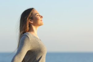 Donna di profilo al mare con espressione che suggerisce liberazione dallo stress
