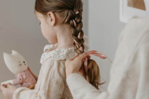 Una mamma che fa una treccia a una bambina