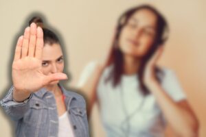 donna che ascolta musica con cuffie e un'altra che fa stop con le mani
